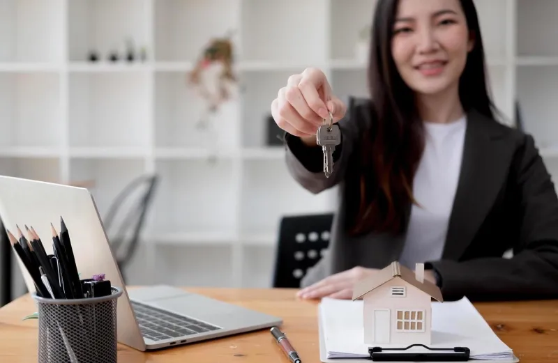 A property agent handing over keys at her desk