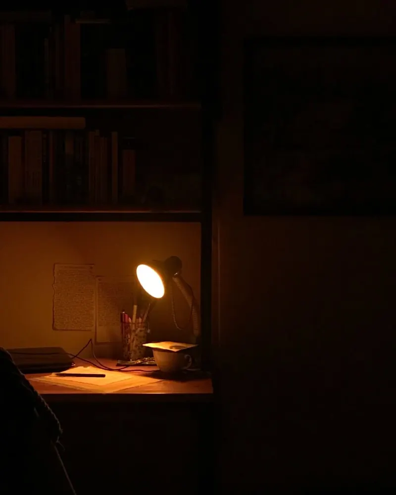 A desk lit by a lamp at night