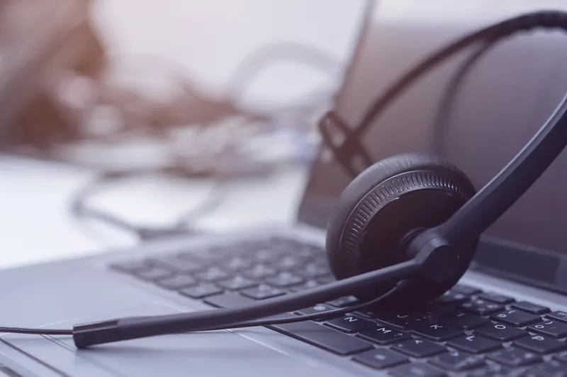 A headset resting on a desk beside a keyboard