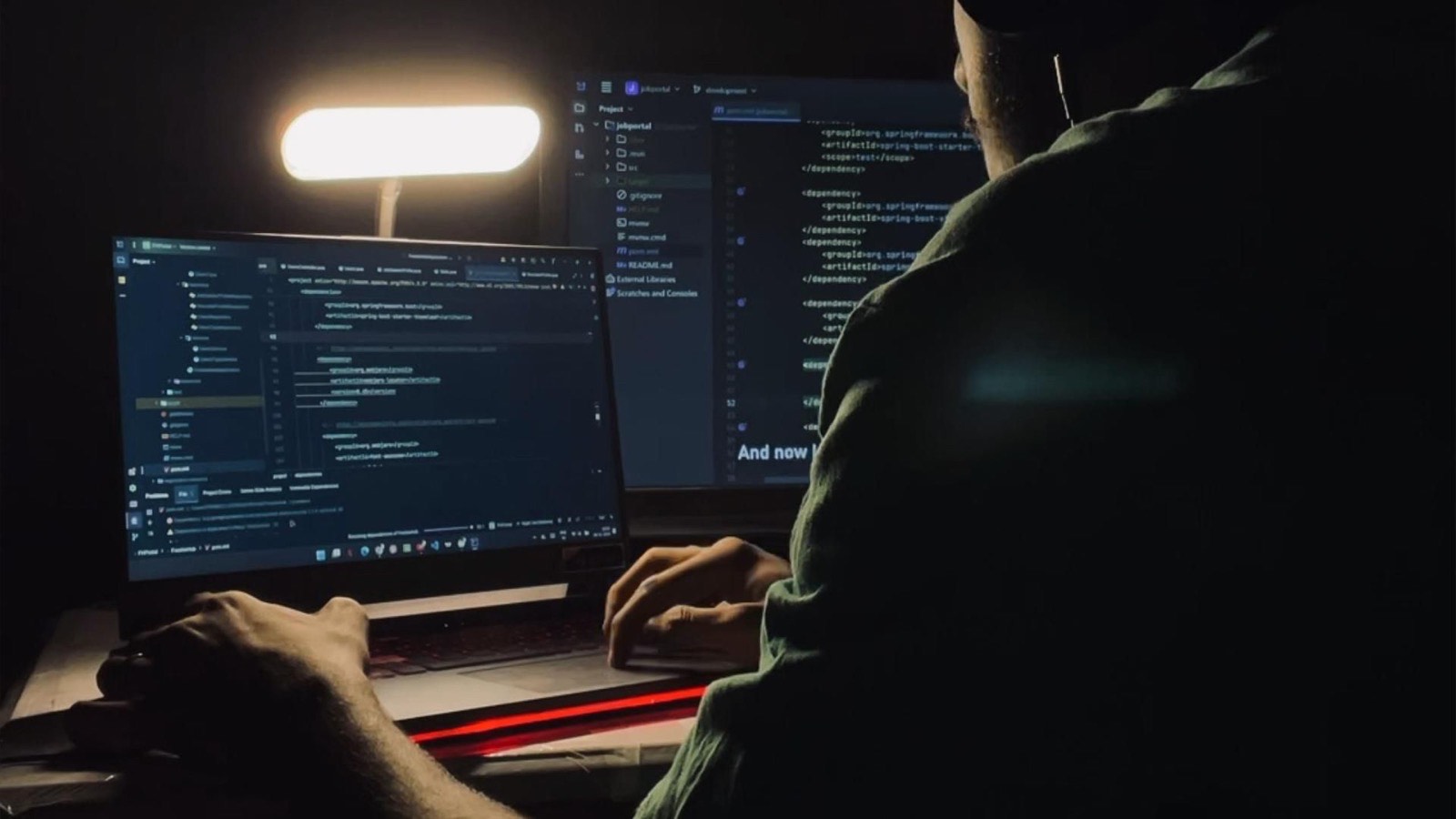 An engineer working on code at a desk in a dark room