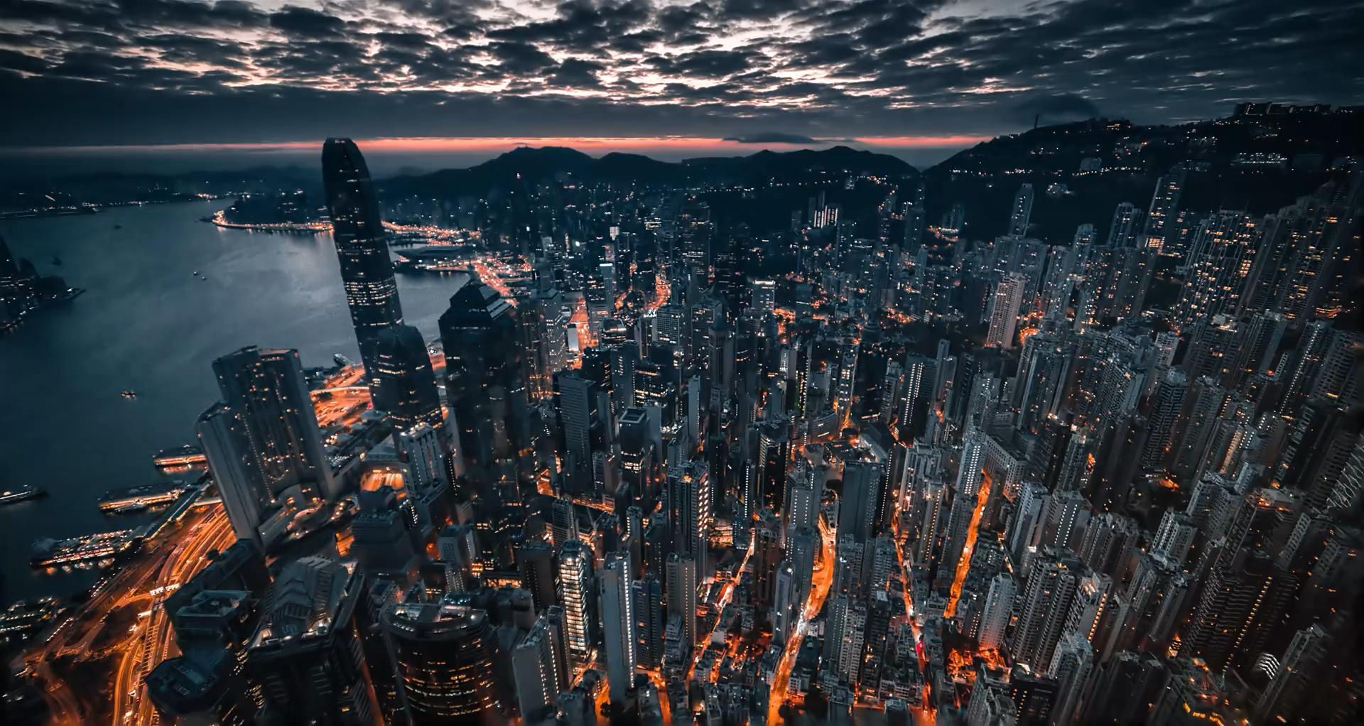 A city at dusk seen from above, with lit highways running through it